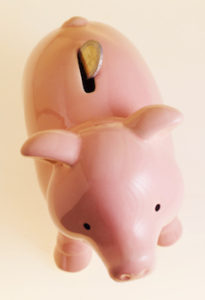 Close-up of a piggy bank with a two euro coin sticking out of top --- Image by © Royalty-Free/Corbis